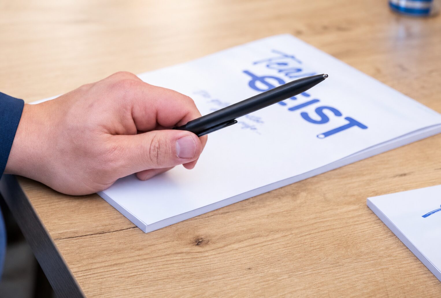 Hand mit Stift auf einem GEIST-Notizblock