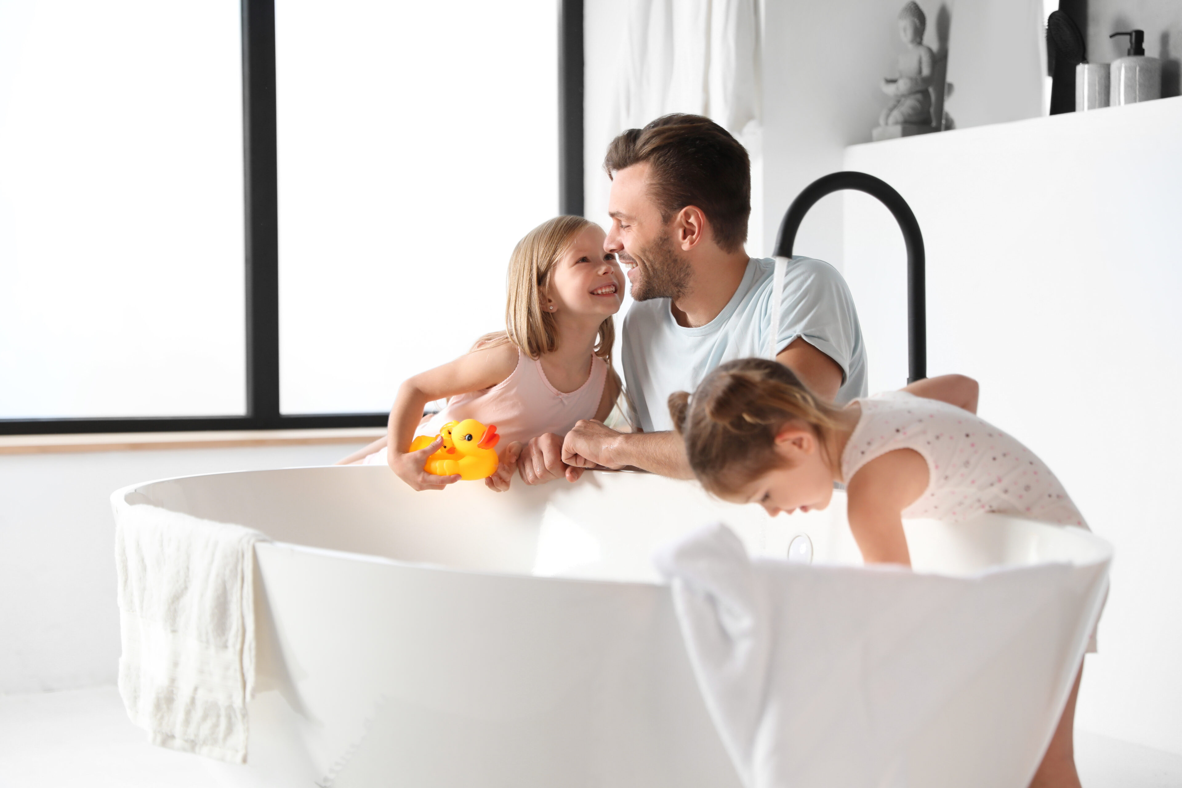 Vater mit zwei Kindern an der Badewanne in einem modernen Bad