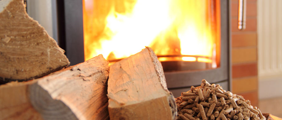 Scheitholz und Holzpellets vor dem Feuer eines Biomassekessels