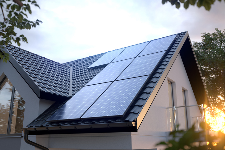 Photovoltaikmodule auf dem Ziegeldach eines Wohnhauses in der Abendsonne