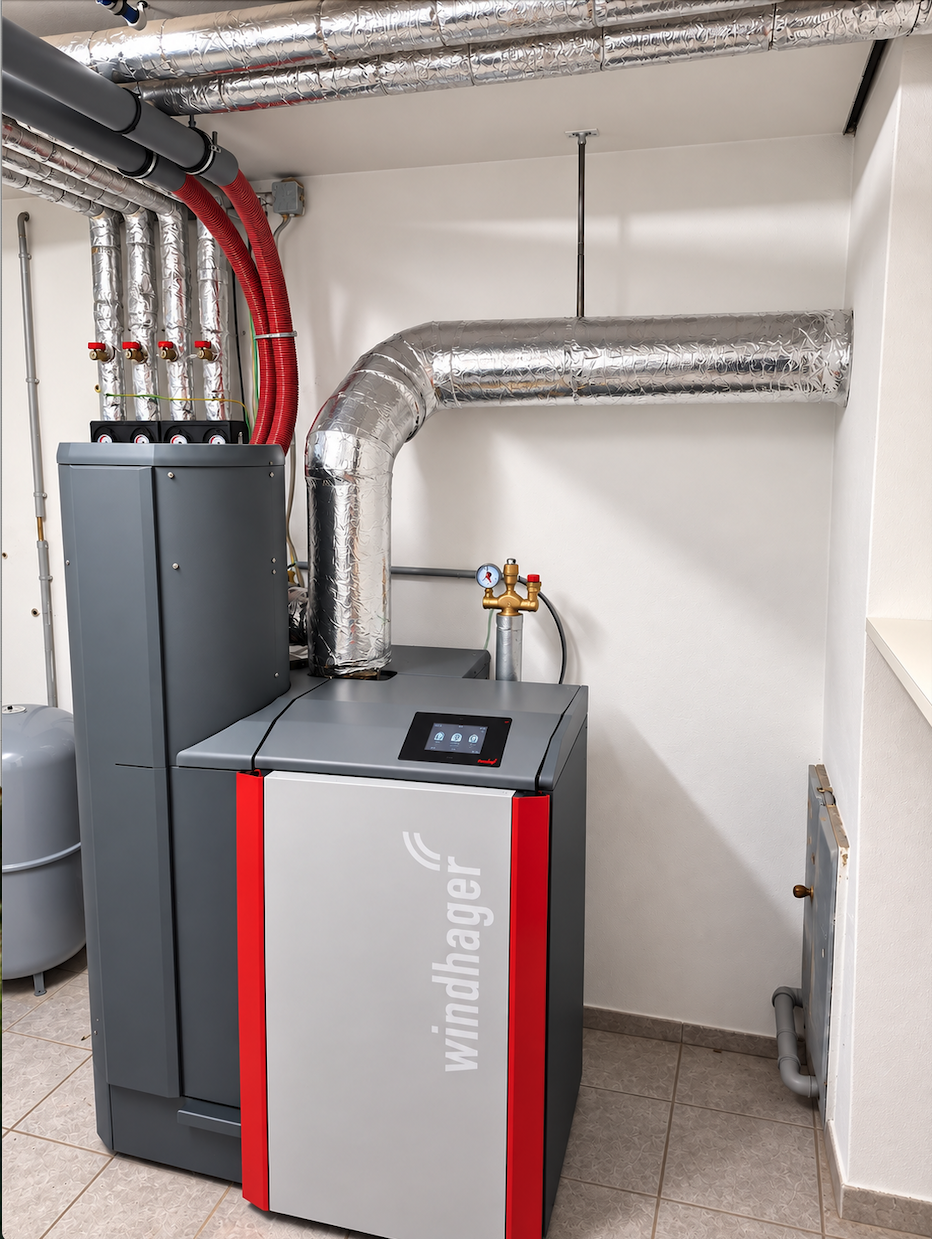 Neuer Windhager-Biomassekessel neben dem Pufferspeicher im Heizraum