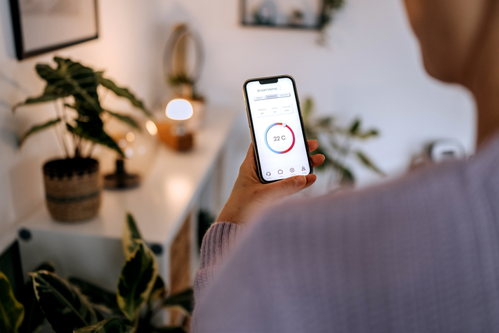 Person steuert die Heizung über eine App am Smartphone
