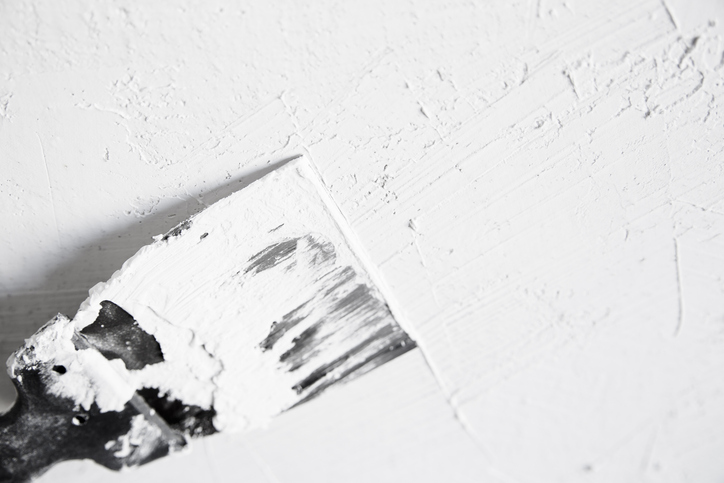 Spachtel zieht weiße Spachtelmasse auf eine Wand